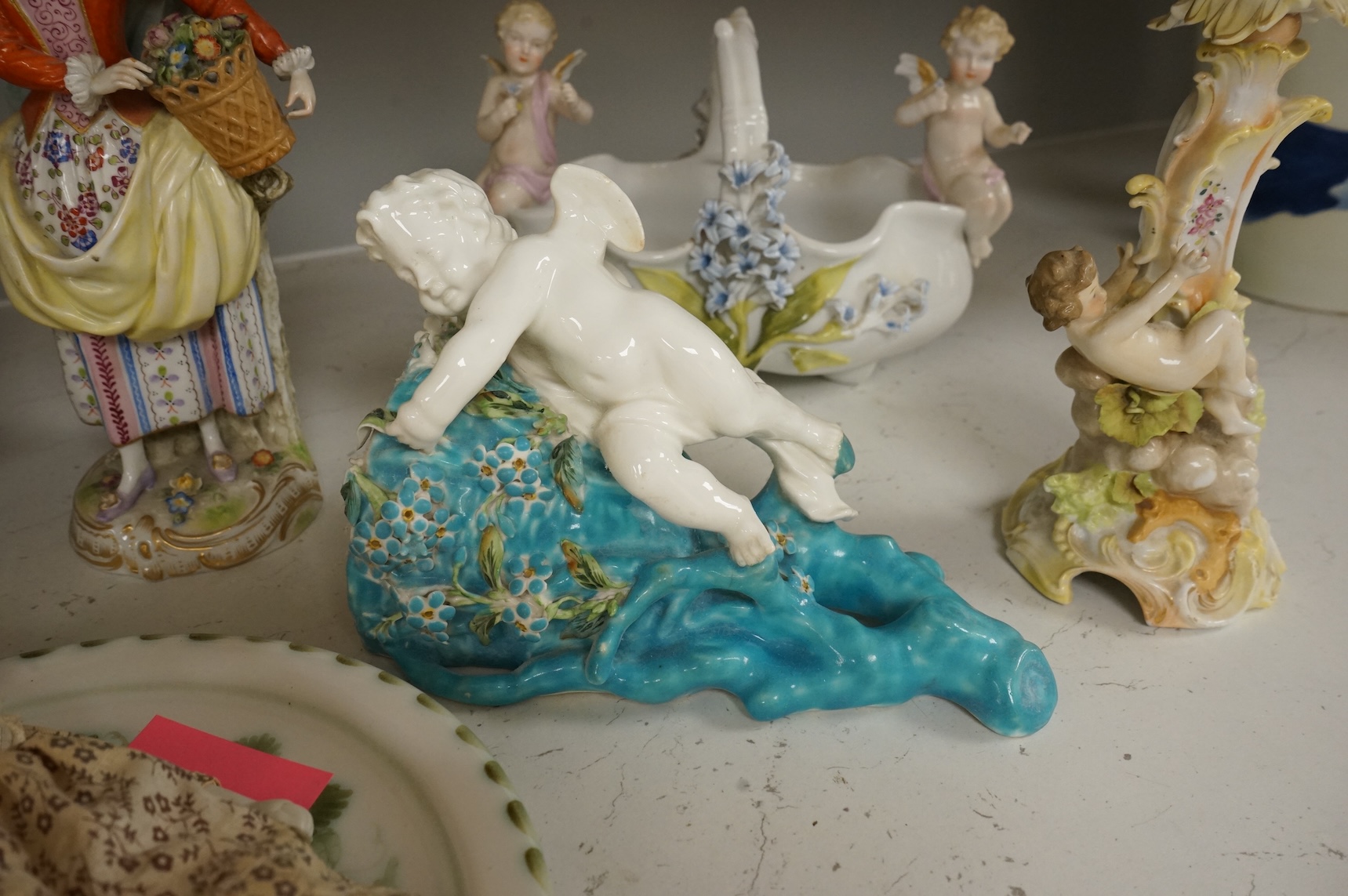 A pair of Sitzendorf figurines, damage to one, a pair of candlesticks, a Rye pottery dish, a Moore Bros. wall pocket, a doll and a basket, tallest 22.5cm